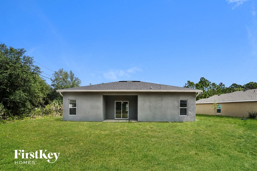 a small gray house with a grass yard and a blue sky