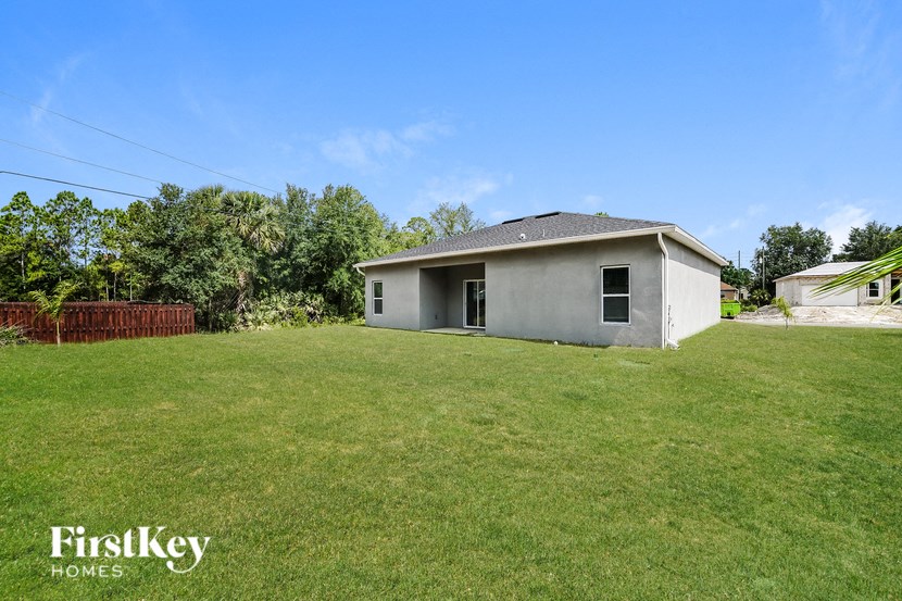 a small gray house with a grassy yard in front of it