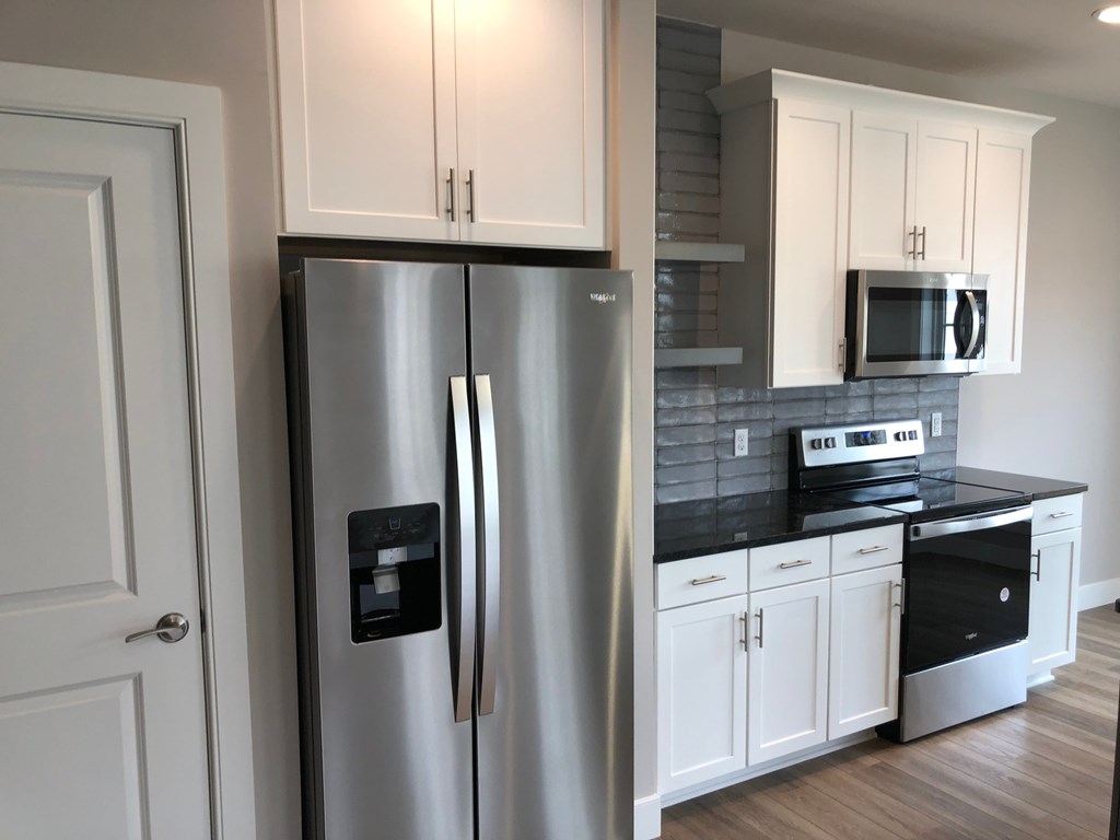 a kitchen with a stainless steel refrigerator and white cabinets