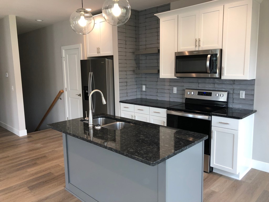 a kitchen with white cabinets and a black counter top