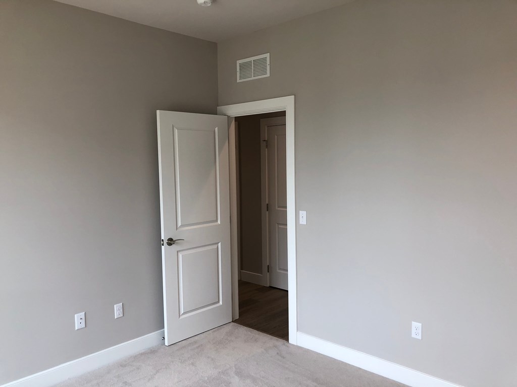 a room with a white door and a hallway with a door open to a closet