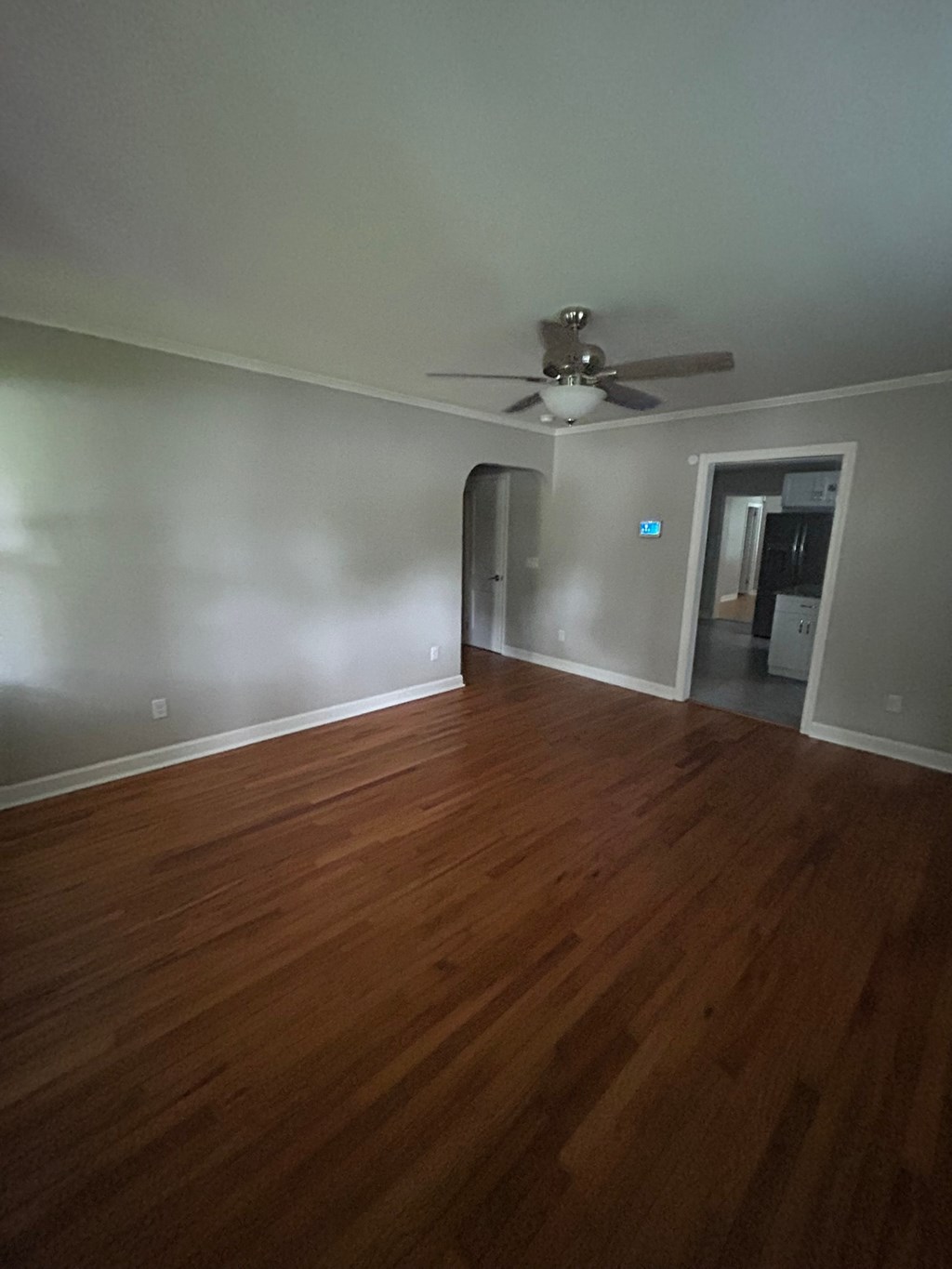 A room with a ceiling fan and wooden floors.
