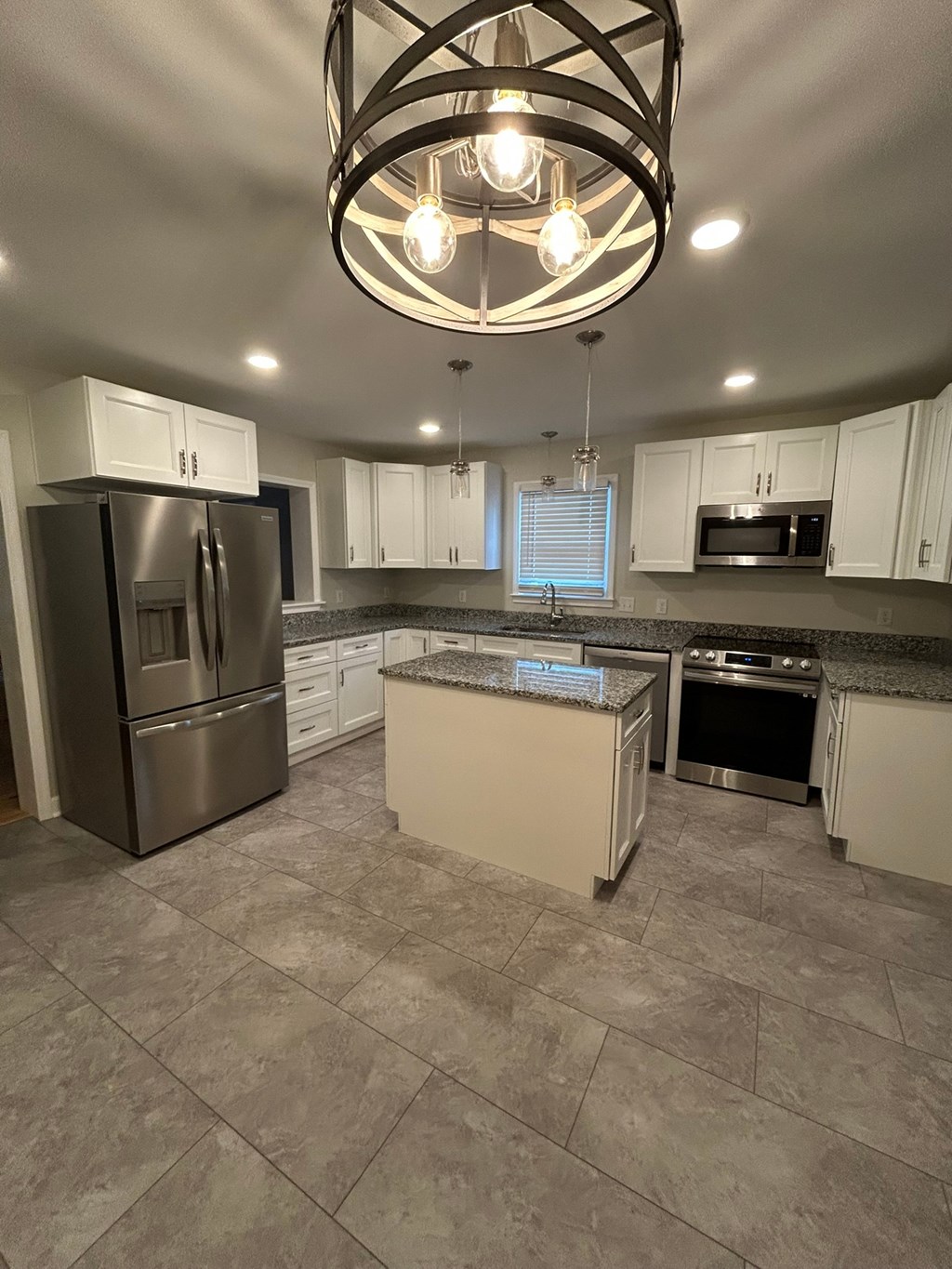A kitchen with a refrigerator, microwave, and oven.