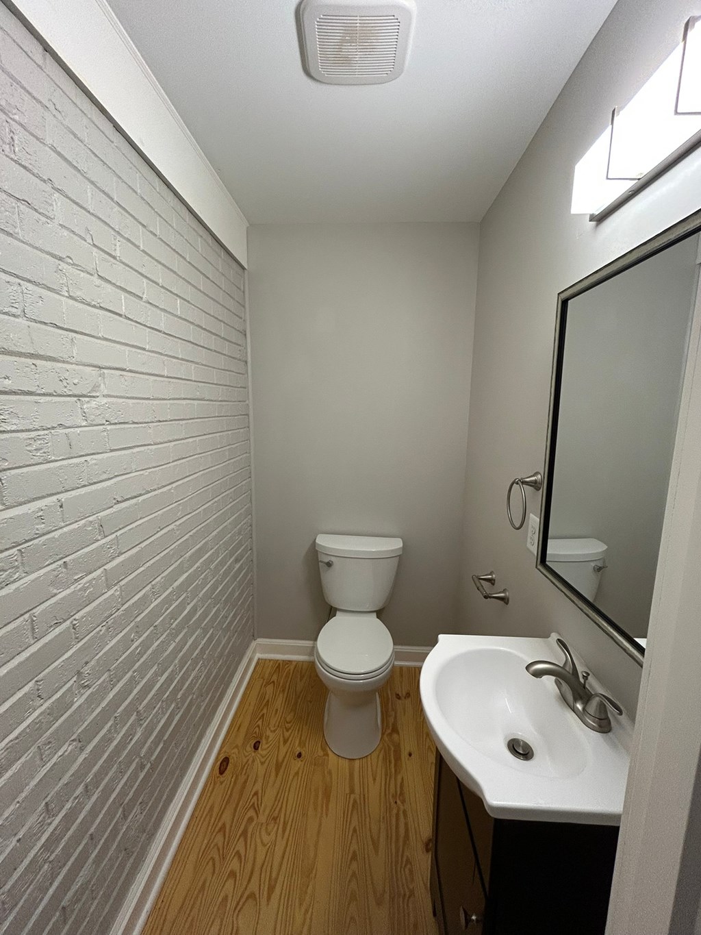 A white toilet sits in a small bathroom with a white sink and a mirror.