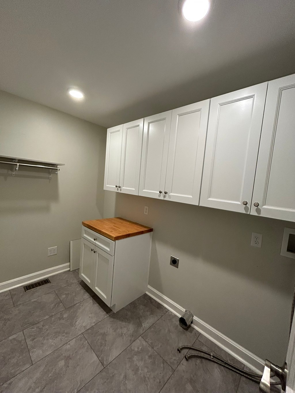 A kitchen with white cabinets and a wooden countertop.