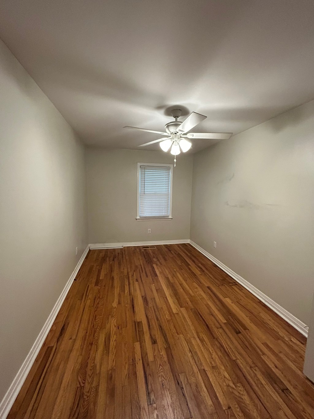A room with wooden floors and a ceiling fan.