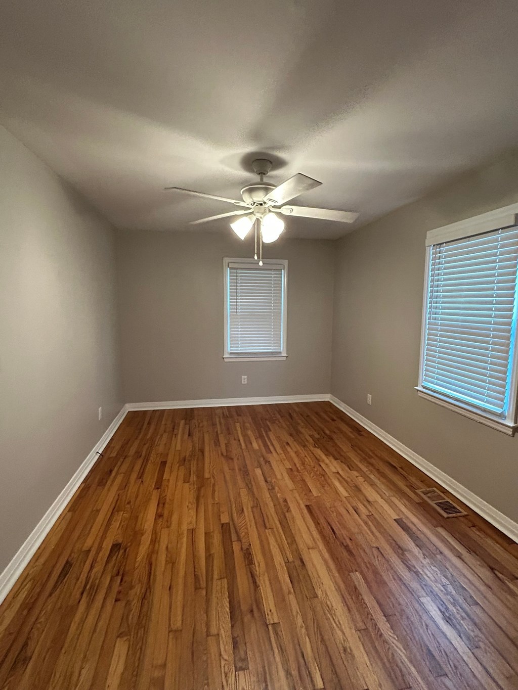 A room with wooden floors and a ceiling fan.