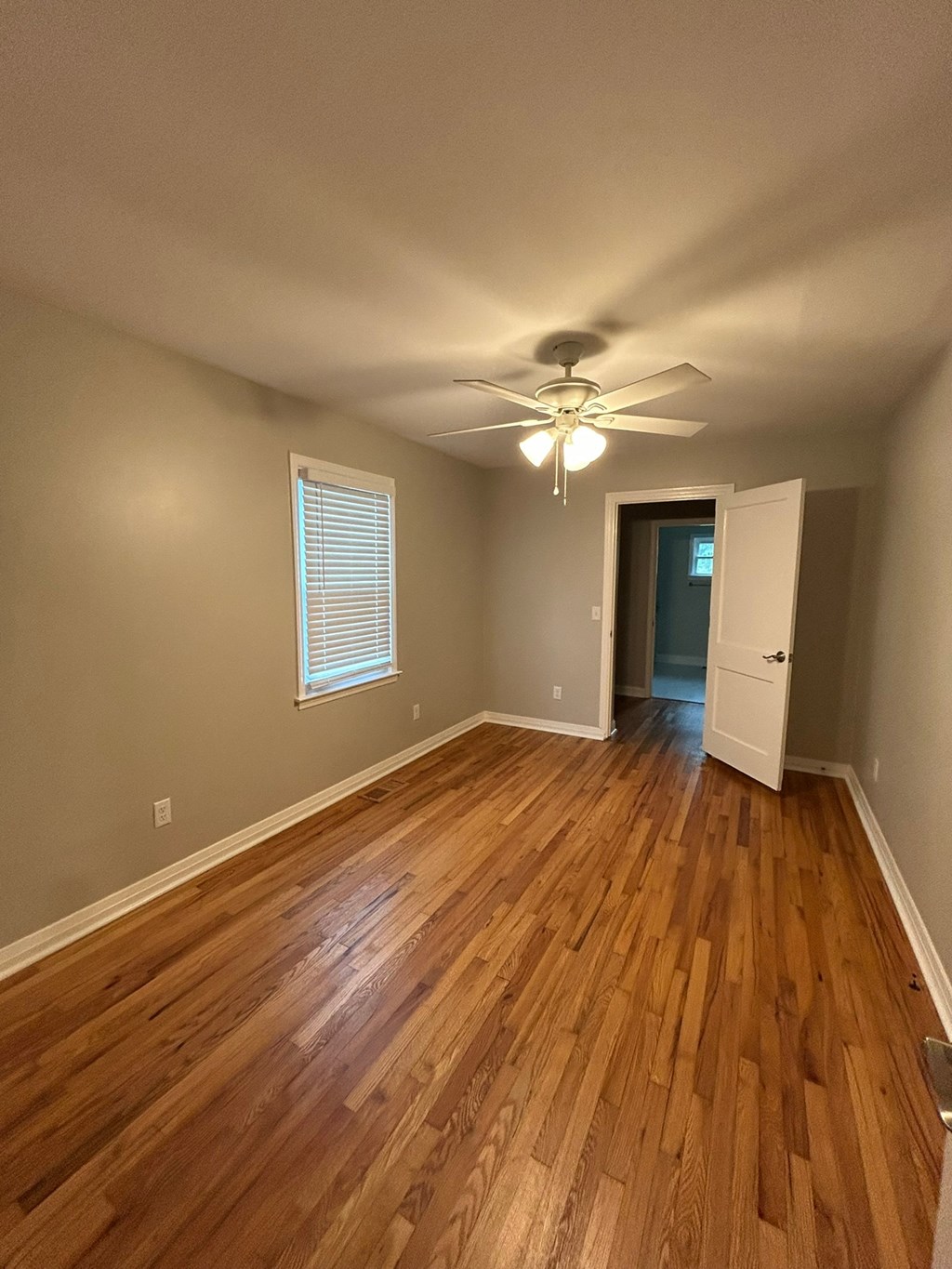 A room with wooden floors and a ceiling fan.