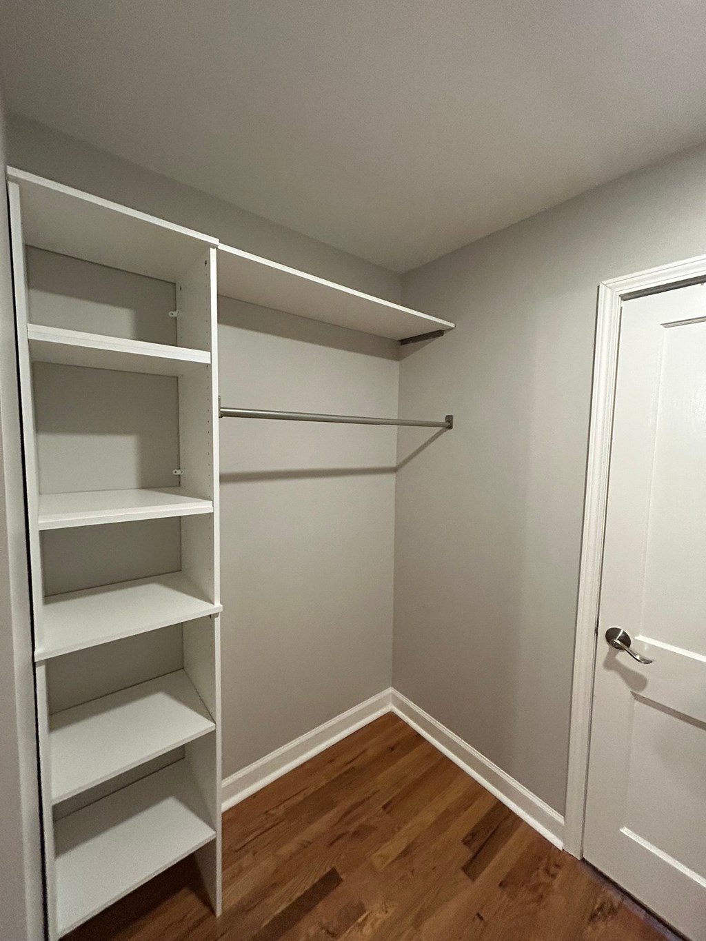 A white closet with a door and shelves.
