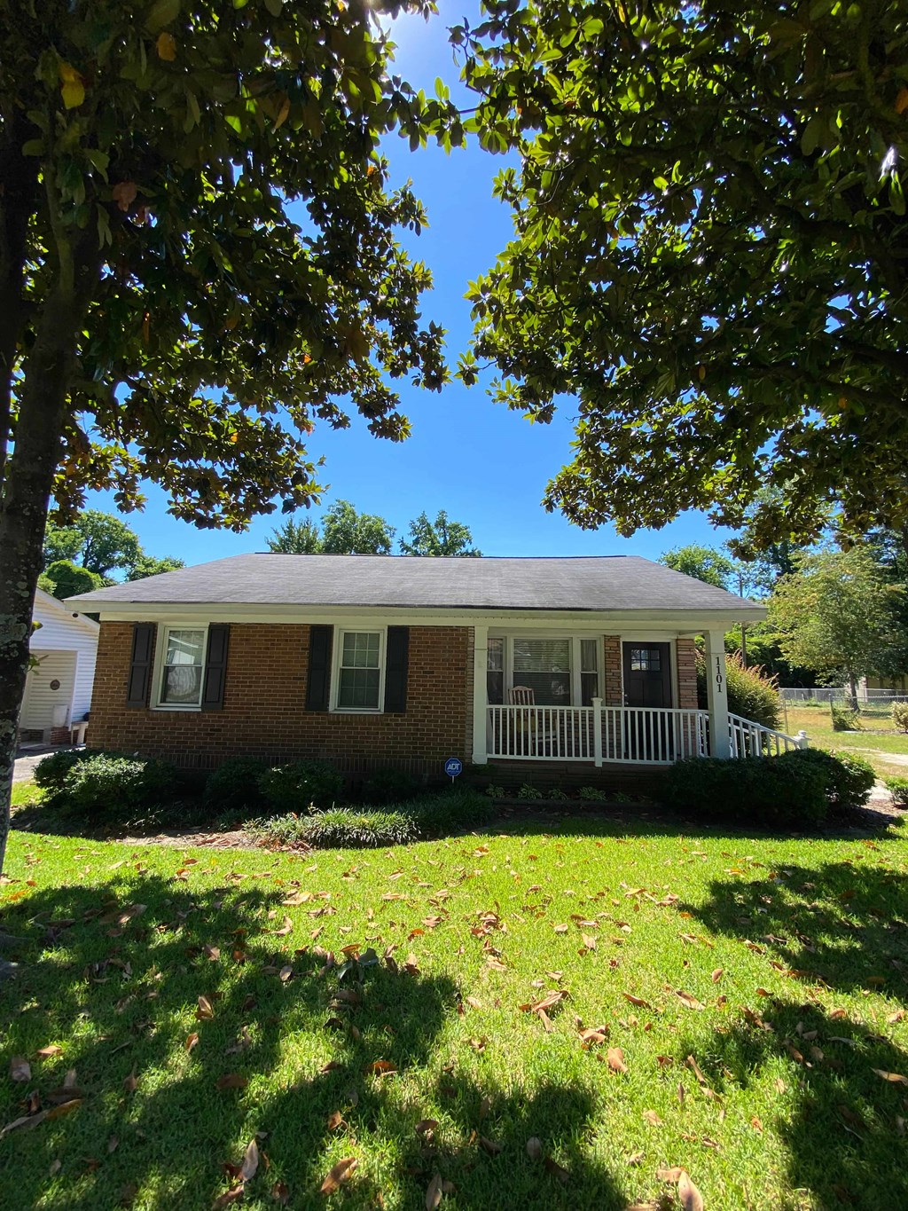 A house with a porch and a tree in front.