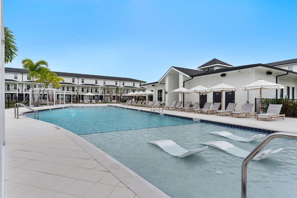 a swimming pool with chairs and umbrellas in front of a building