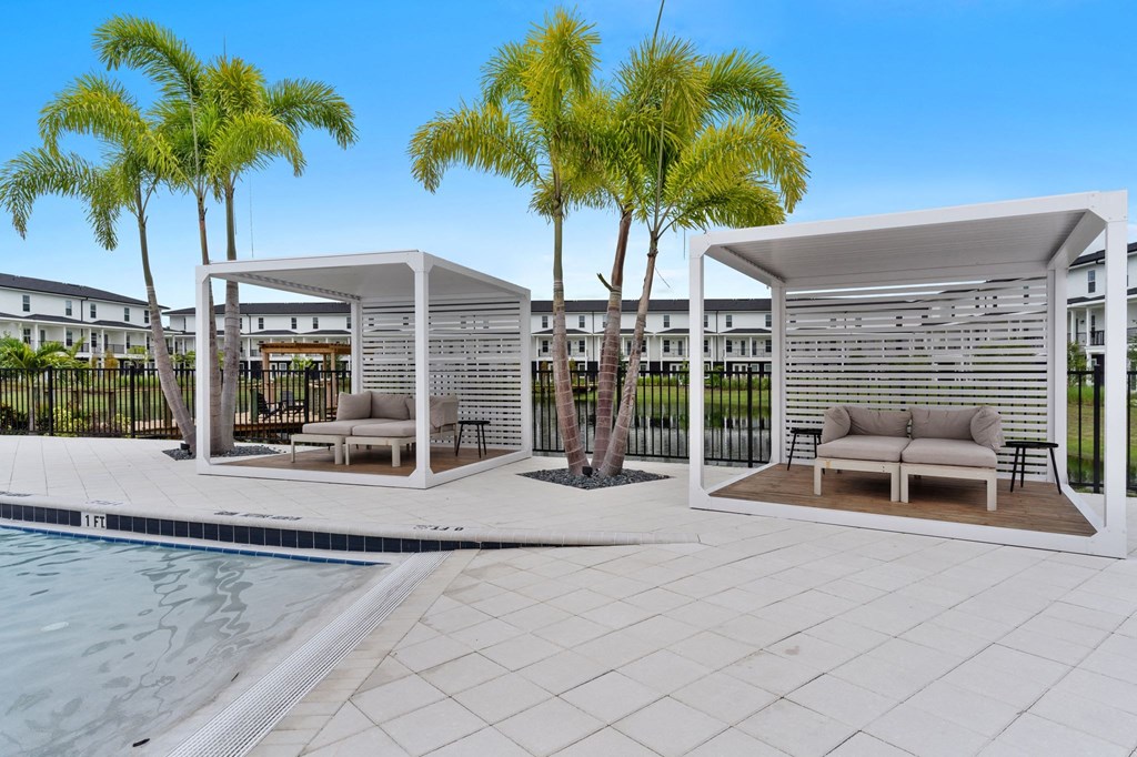 a swimming pool with two couches and palm trees