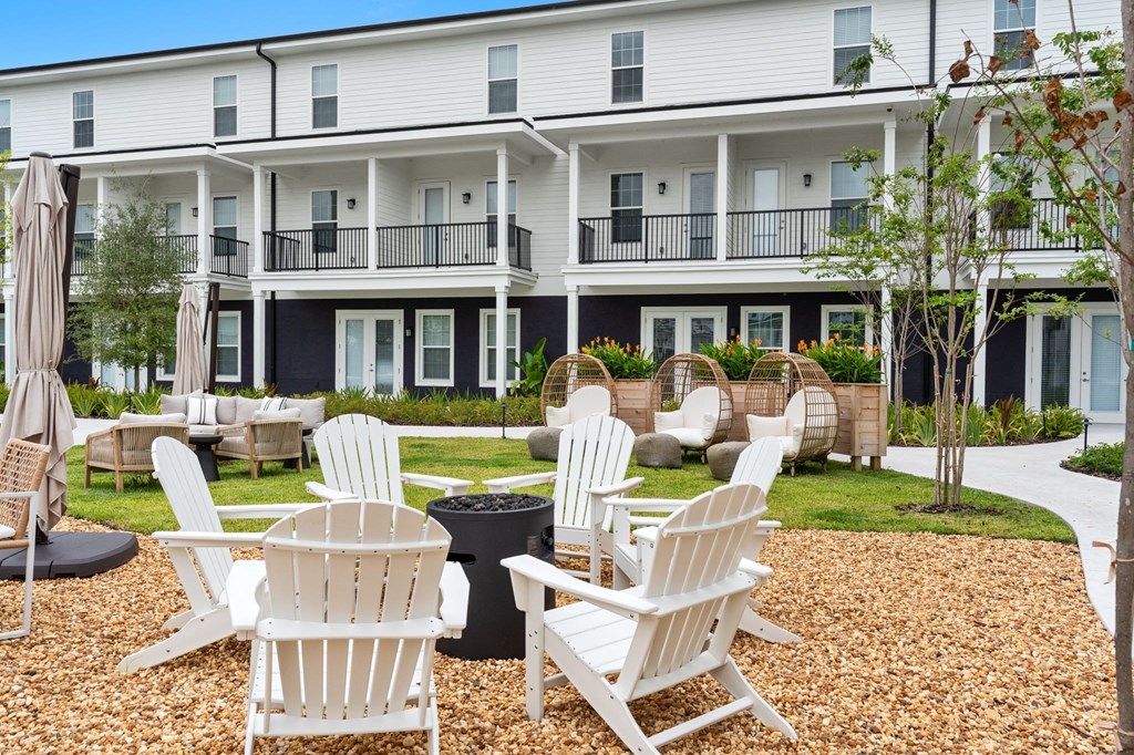 a courtyard with chairs and tables in front of an apartment building