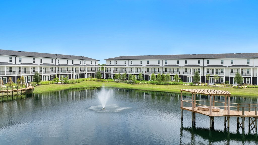a fountain in the middle of a pond with houses in the background