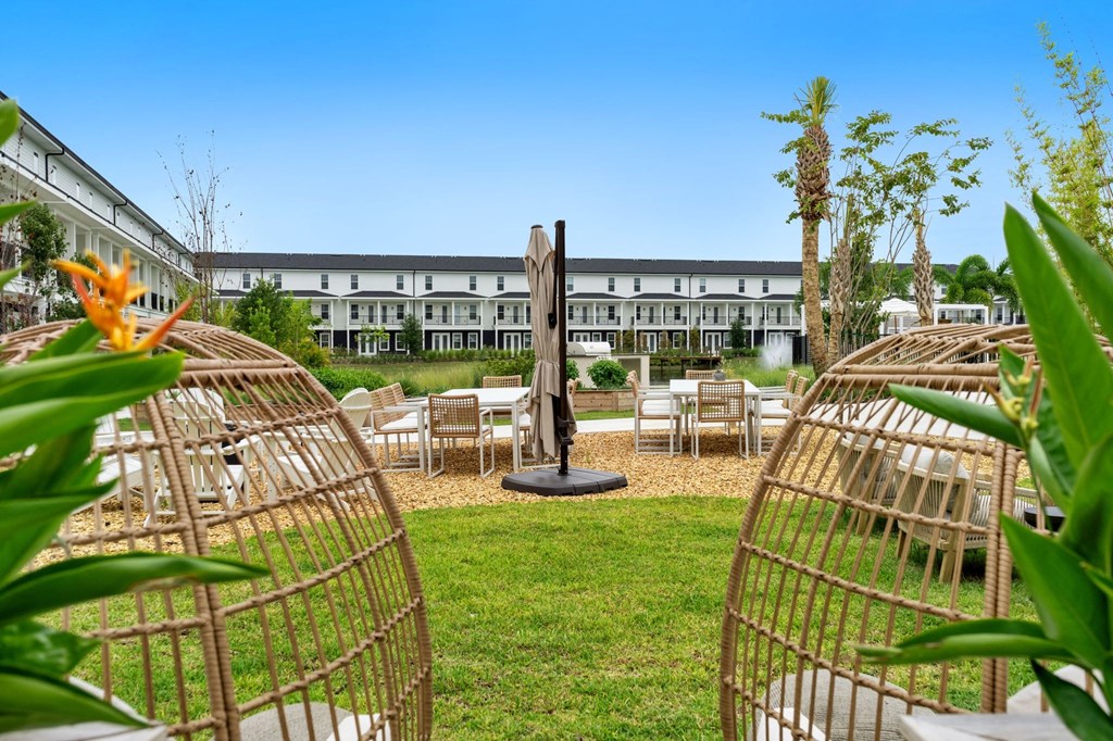 a garden with tables and chairs and a sculpture in the middle