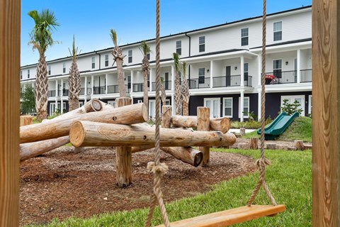 A playground with a swing set in front of a building.