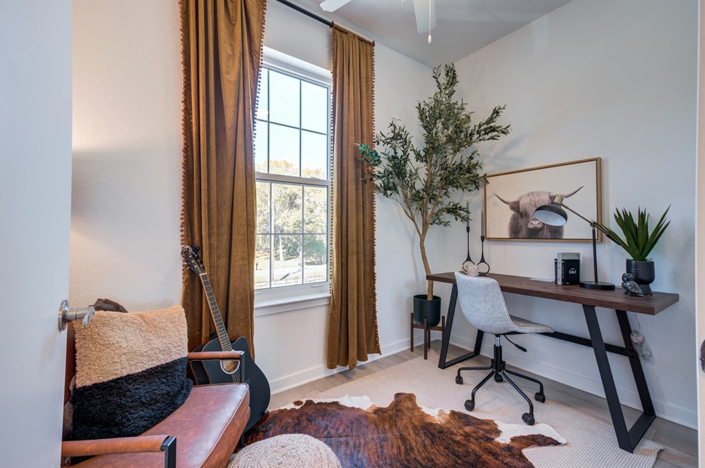 an office with a desk and a guitar in a room with a window