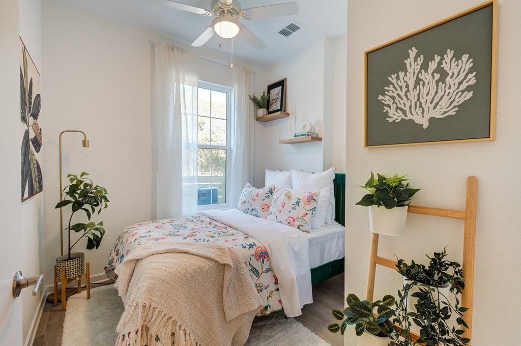 a bedroom with a bed and plants and a ceiling fan