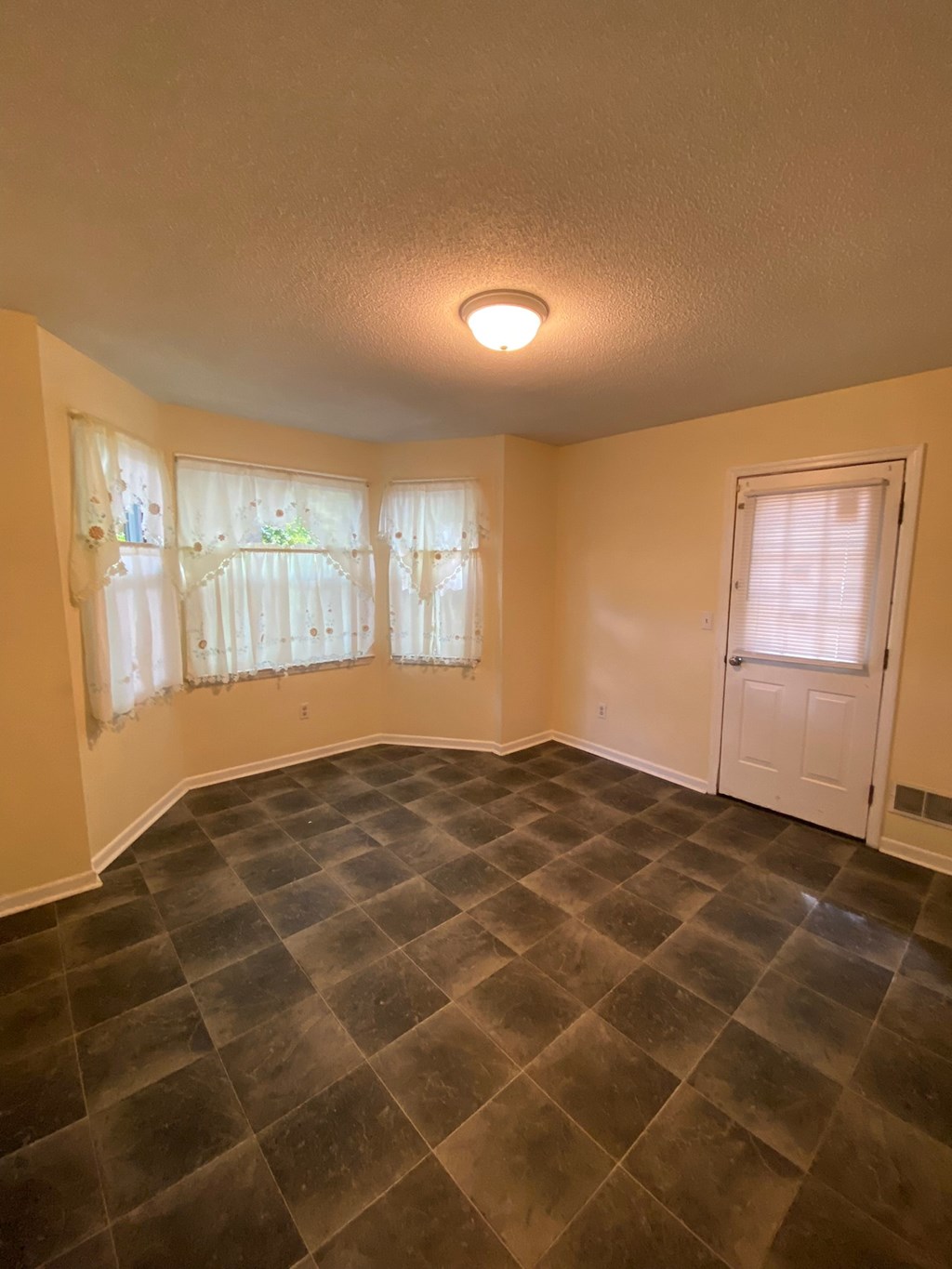 an empty living room with tile floors and a white door