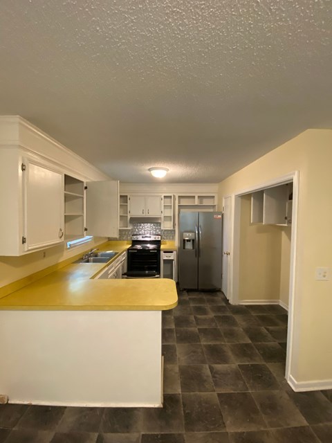 a kitchen with white cabinets and a black stove and a refrigerator