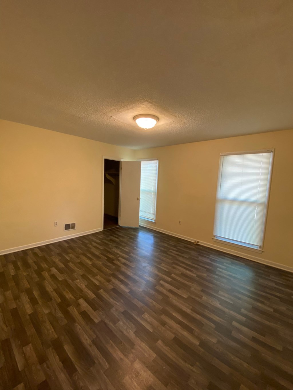 an empty living room with wood floors and a window