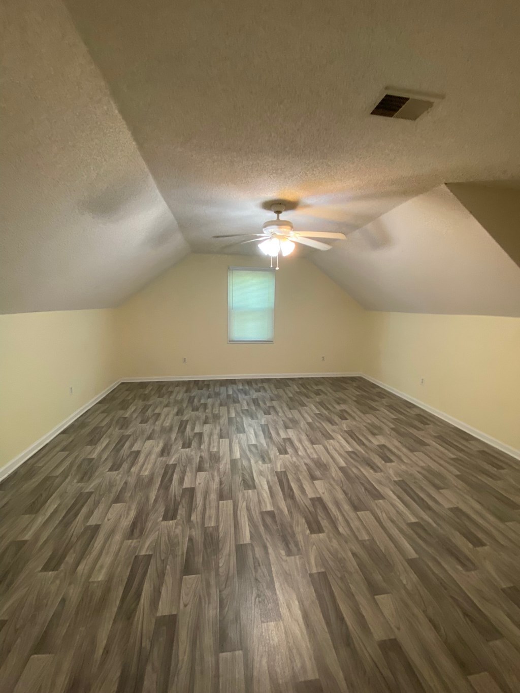 an empty living room with wood floors and a ceiling fan