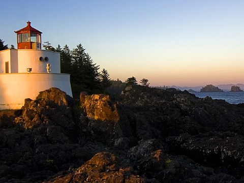 A lighthouse stands on a rocky outcrop by the sea.