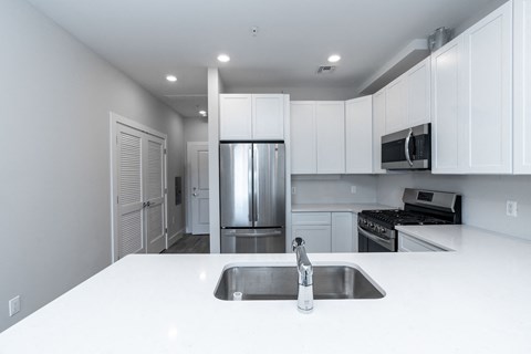 a kitchen with white counter tops and a stainless steel refrigerator