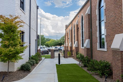 the sidewalk in front of a brick building with green grass