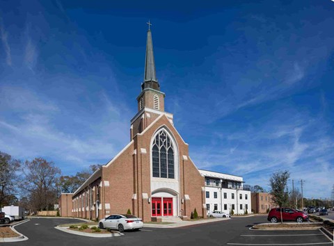 a church with a tall steeple and a red and white building
