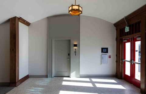a large lobby with red doors and a light shining through the window