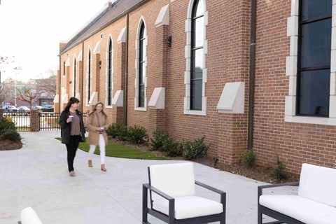 two women walking outside of a brick building