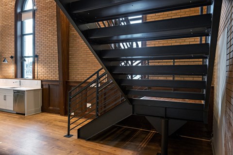 a black staircase in a room with brick walls and wood floors