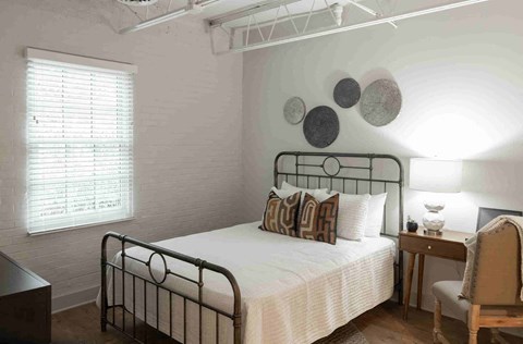 a bedroom with a bed and a desk and a window