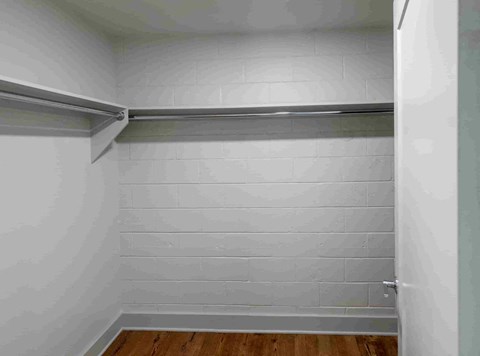 the closet in a small room with white walls and wood floors