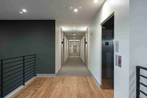 a long hallway with wood floors and black railings and white walls