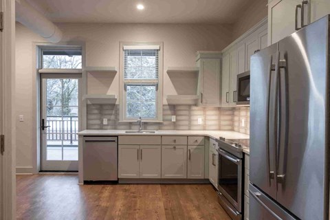 an empty kitchen with stainless steel appliances and white cabinets