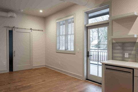 an empty living room with a door to a kitchen