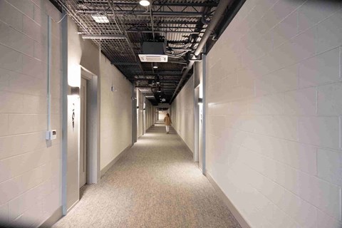 a long corridor with white walls and white doors and a person walking down the end