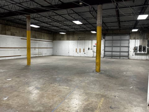 the inside of a warehouse with poles and a garage door