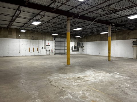 the inside of a warehouse with concrete floors and yellow poles