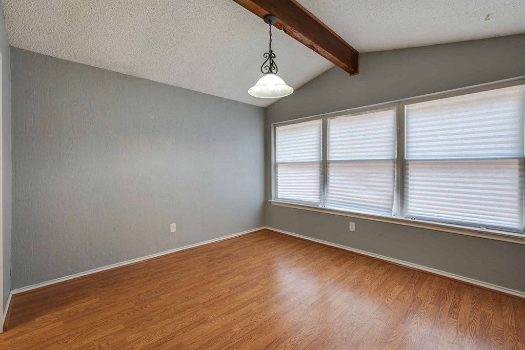 an empty living room with wood floors and large windows