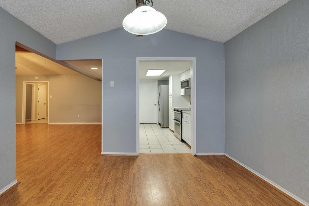 an empty living room and kitchen with a hard wood floor