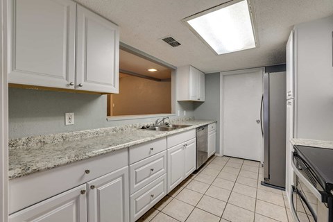 a kitchen with white cabinets and a sink and a refrigerator