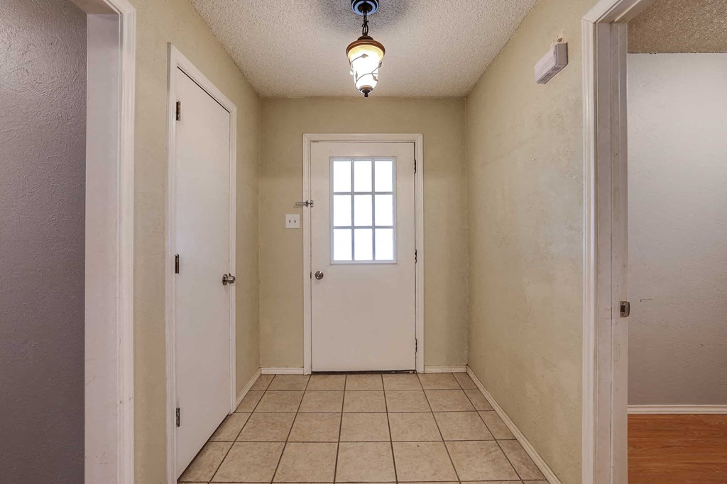 an empty hallway with a white door and a window