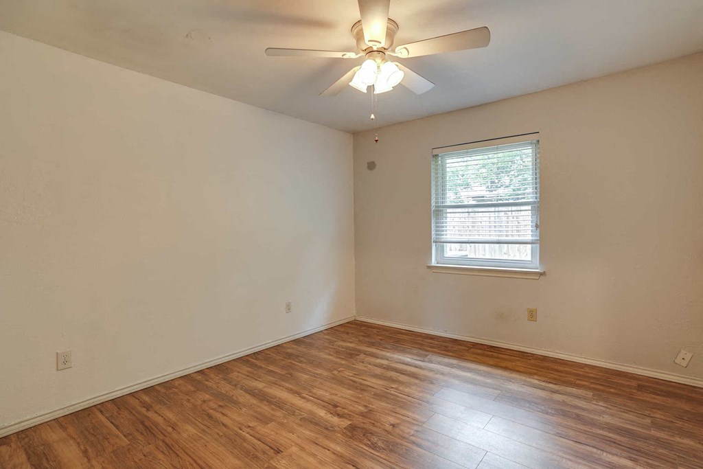 an empty living room with a ceiling fan and a window