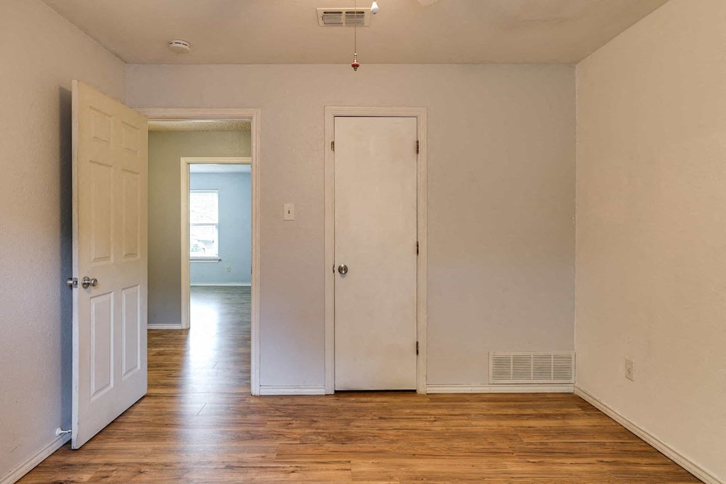 a room with wood floors and white walls and a closet