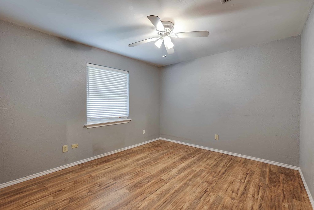 an empty living room with wood floors and a ceiling fan