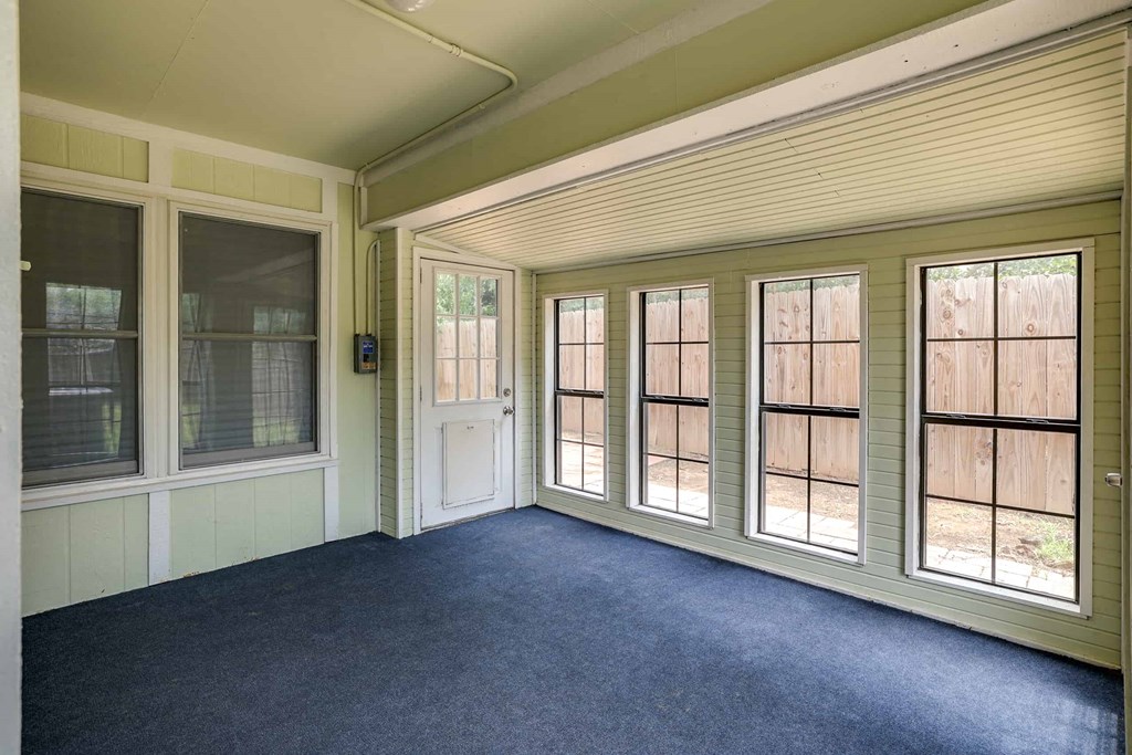 a room with windows and blue carpet and a door