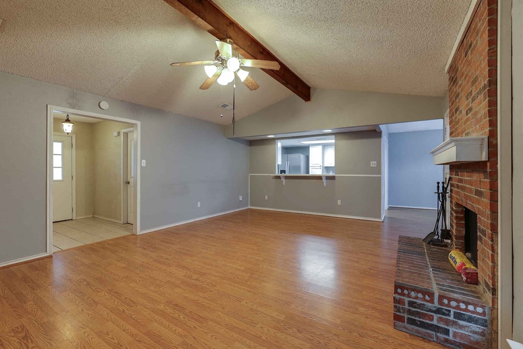 an empty living room with a fireplace and a ceiling fan